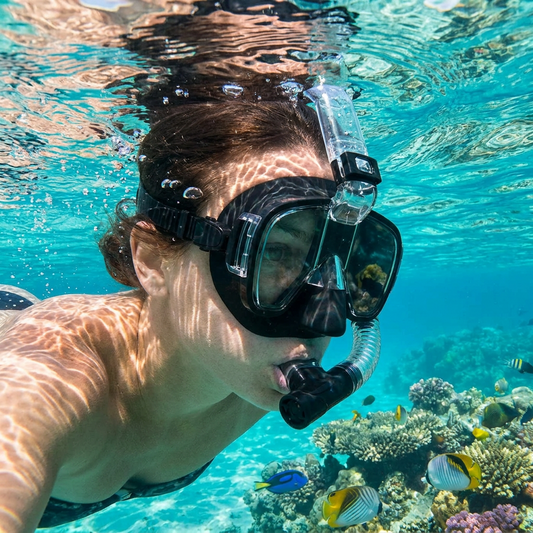 Person wearing a snorkeling mask with dry top system in clear ocean water