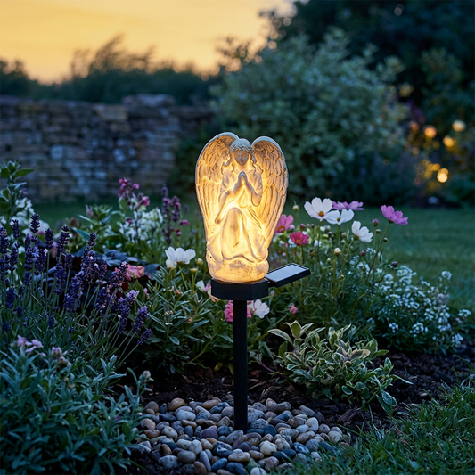 Solar angel garden light glowing in a flower bed